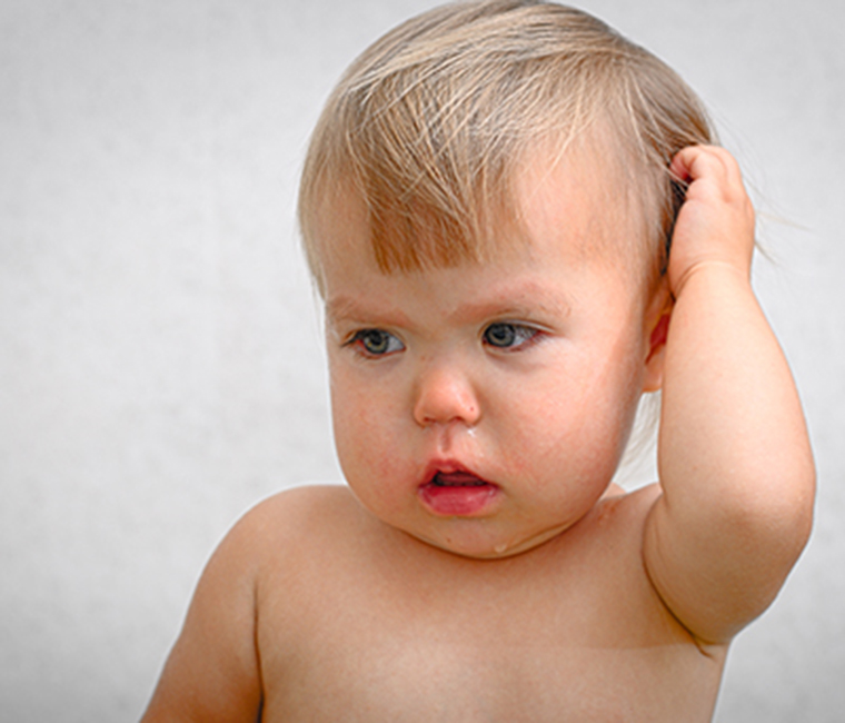 sick baby holding ear